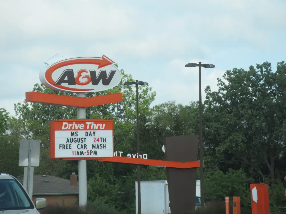 Hohes Schild eines A&W-Drive-Thru-Restaurants an einer amerikanischen Ausfallstraße, darunter eine Anzeigetafel
