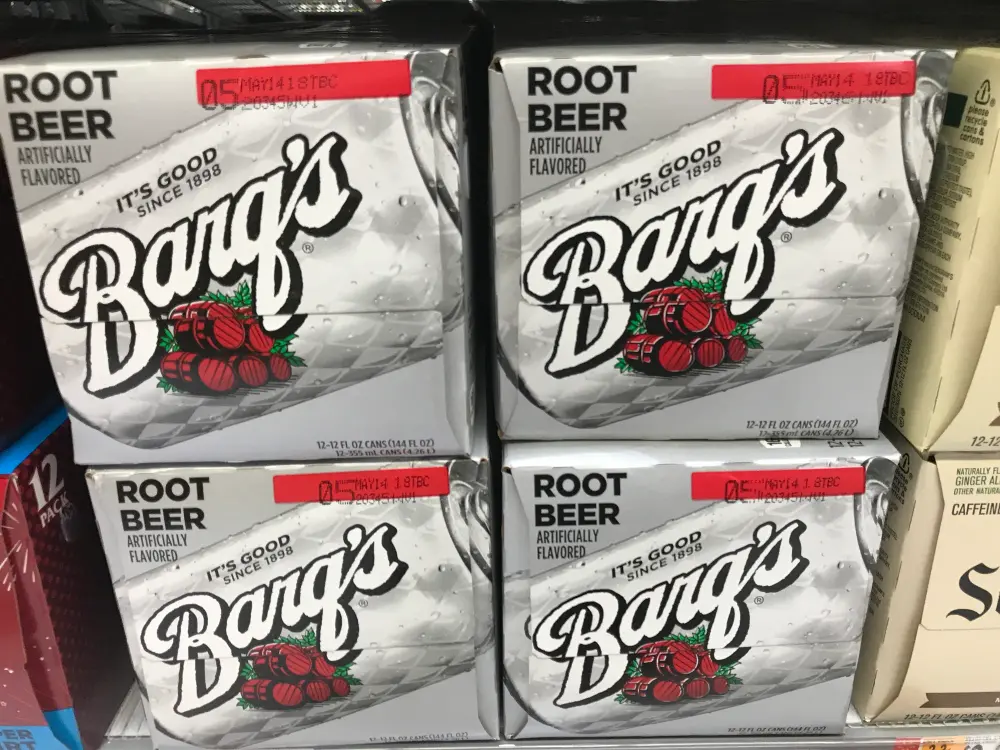 Vier Zwoelferkartons Barq's Root Beer im Regal eines US-Supermarkts, Aufschrift It's Good Since 1898