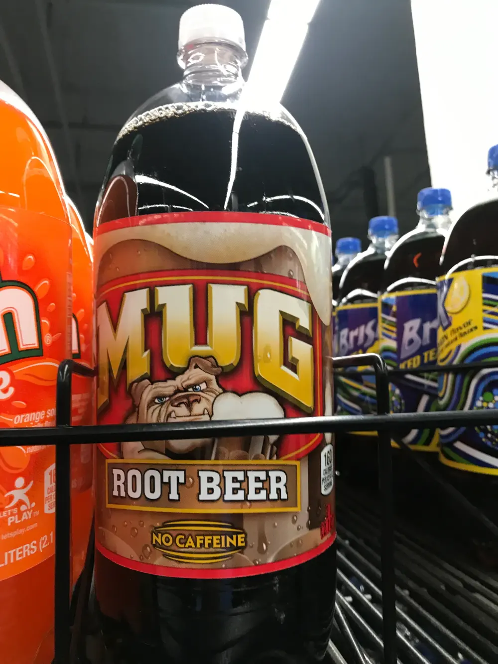 Zwei-Liter-Flasche Mug Root Beer mit der Bulldogge auf dem Etikett und dem Hinweis No Caffeine, im Regal zwischen anderen Limonaden